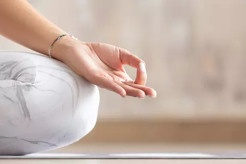 Frau sitzt auf einer Yoga-Matte und meditiert
