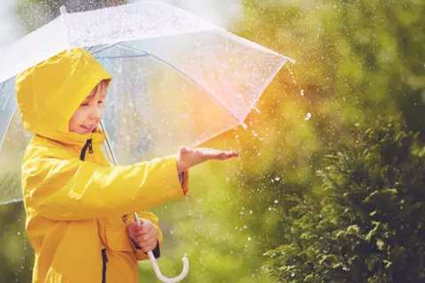 Junge steht mit einem Schirm im Regen