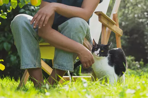 Frau sitzt mit einer Katze im Garten