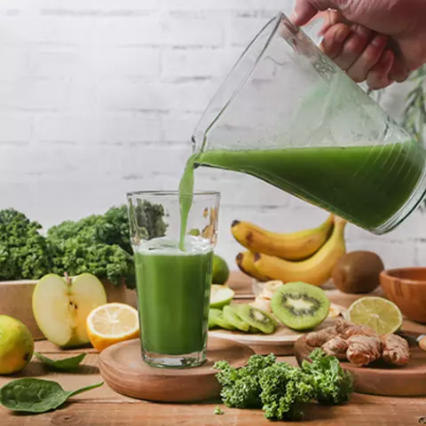 Glas mit grünem Saft aus verschiedenem Obst und Gemüse